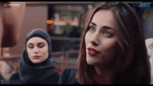 a woman in a hijab is sitting next to another woman in a restaurant .
