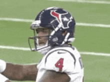 a football player wearing a helmet and number 4 jersey is standing on the field .