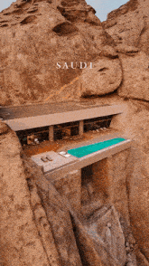 a house with a swimming pool in the middle of a rocky cliff with the word saudi on the bottom