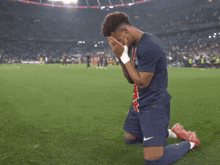 a soccer player is kneeling down with his hands on his face