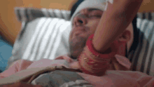 a man with a bandage on his head is laying in bed with a woman holding his arm .