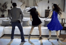 a man and two women are dancing in a living room in front of a white couch .