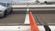 a white car is driving down a road with a sign that says yoooooooh
