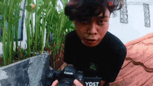 a young man is holding a canon camera