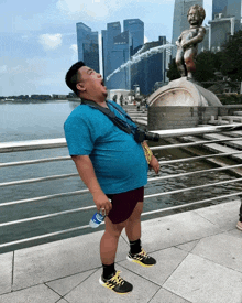 a man in a blue shirt holds a bottle of aquafina water in his hand