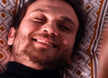 a man with a beard is smiling while laying down