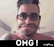 a shirtless man with glasses and a tattoo on his arm is making a funny face and says omg !