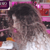 a woman with curly hair stands in front of a sign that says rato endo