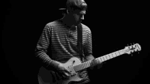 a man in a striped shirt is playing an epiphone guitar in a black and white photo