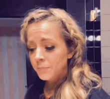 a woman with a braid in her hair is crying and making a funny face .