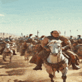 a man wearing glasses is riding a white horse in front of a crowd of soldiers