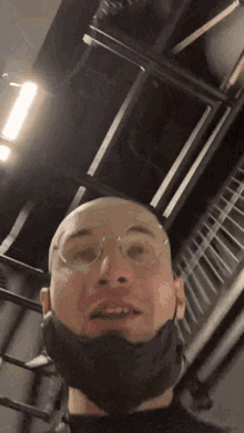 a man wearing glasses and a mask looks up at the camera