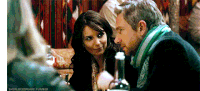 a man and a woman are sitting at a table with a bottle of wine ..