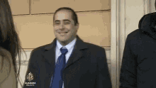 a man in a suit and tie is smiling and wearing a jacket that says aljazeera on it