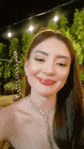 a woman wearing a necklace and earrings is smiling for the camera