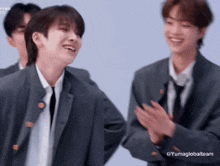 a group of young men in suits and ties are clapping and laughing .