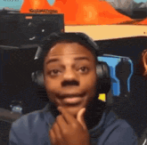 a man wearing headphones looks at the camera with his hand on his chin