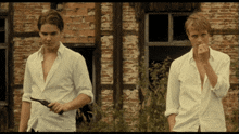two men in white shirts standing in front of a brick building
