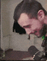 a man with a beard is sitting in a room with a microphone .