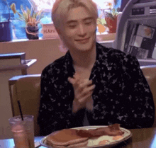 a man is sitting at a table with a plate of food and a glass of water .