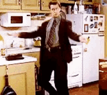 a man in a suit and tie dancing in a kitchen
