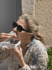 a woman wearing prada sunglasses eating something