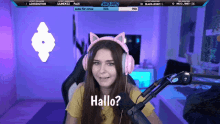 a girl wearing pink headphones says hallo on a screen