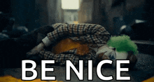 a clown is laying on the ground with the words `` be nice '' written on it .