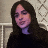 a woman with long dark hair is wearing a black shirt