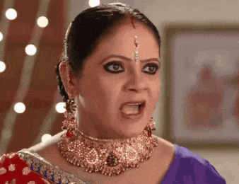a woman wearing a gold necklace and earrings is making a funny face .
