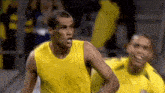 a man in a yellow tank top is standing next to a man in a yellow shirt .