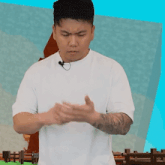 a man with a tattoo on his arm is wearing a white t-shirt and a microphone