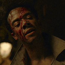 a man with blood on his face is smiling with his eyes closed