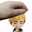 a hand is putting a toy on top of a toy boy .