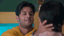 a man in a yellow sweatshirt is hugging a woman in a pink shirt