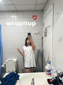 a woman taking a picture of herself in a bathroom with the word wrapitup on the wall