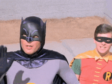 a man dressed as batman and a man dressed as robin are waving
