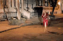 a woman in a red dress is running down a street .