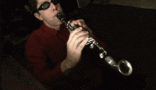 a man wearing sunglasses plays a clarinet