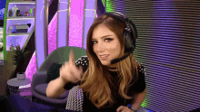 a woman wearing a headset is giving a thumbs up sign
