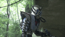 a man in a robot costume is standing in the woods holding a sword