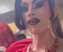 a close up of a woman 's face with makeup and a red top