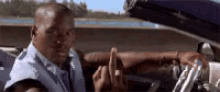 a man is giving the middle finger while sitting in a car .