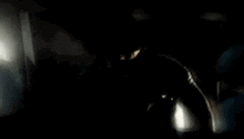 a man in a suit and tie is smoking a cigarette in a dark room .
