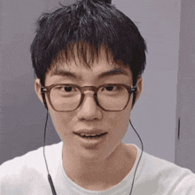 a young man wearing glasses and earbuds is smiling