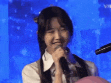 a young girl is singing into a microphone on a stage and smiling .