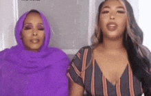 two women are sitting next to each other wearing purple scarves .