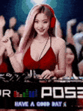 a woman in a red top and headphones is playing music in front of a crowd at a party .