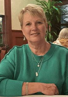 a woman wearing a green sweater and silver necklaces