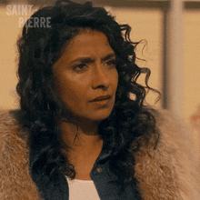 a woman with curly hair is wearing a fur coat and a denim shirt .
